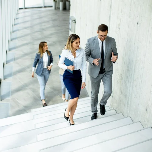 Effizient und verlässlich So arbeiten unsere dedizierten Teams für Ihren Projekterfolg Business-Team steigt gemeinsam eine moderne Treppe hinauf, symbolisiert Fortschritt und Zusammenarbeit